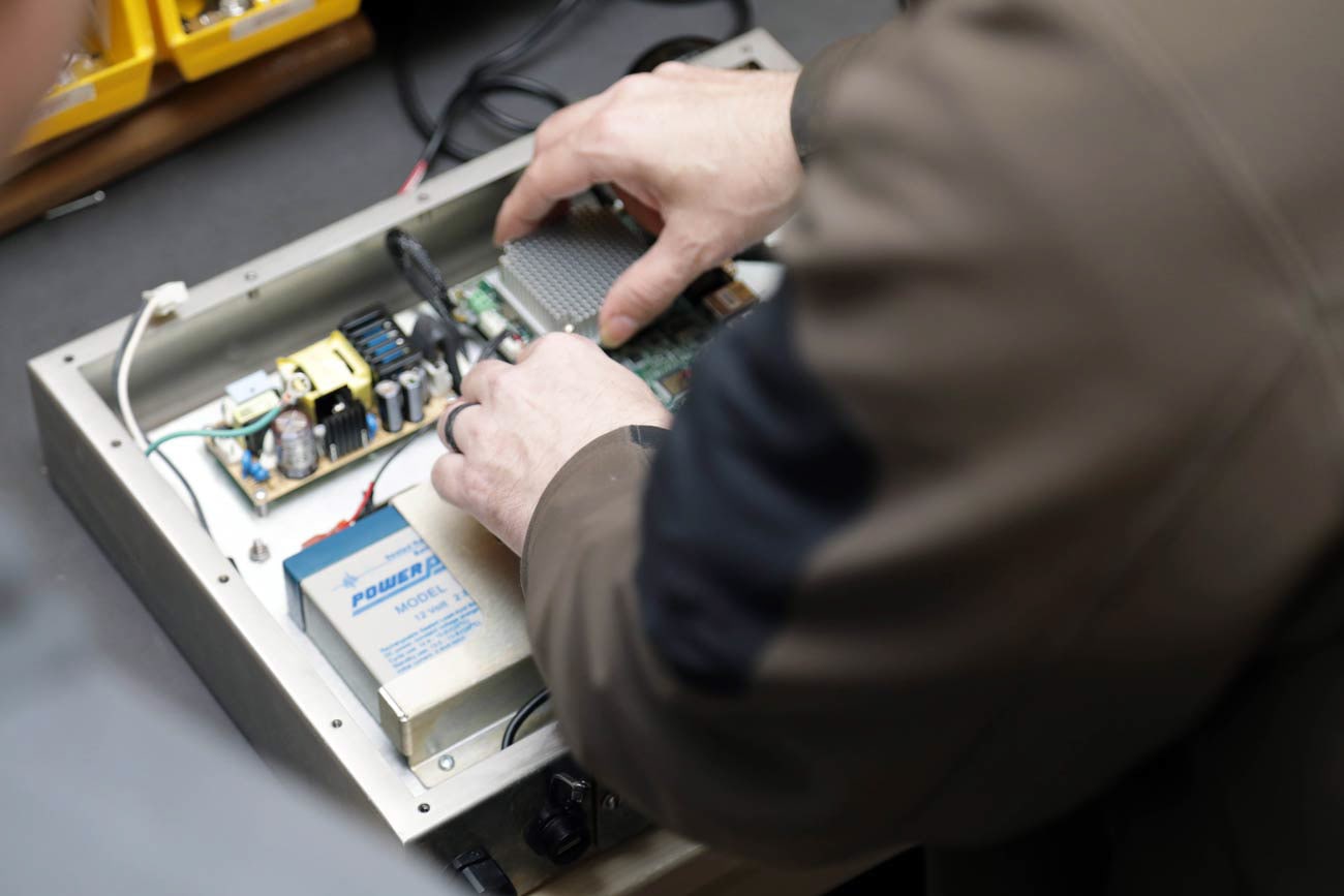 A Process Integration, Inc. technician wiring a power supply into a Softouch enclosure on the assembly bench