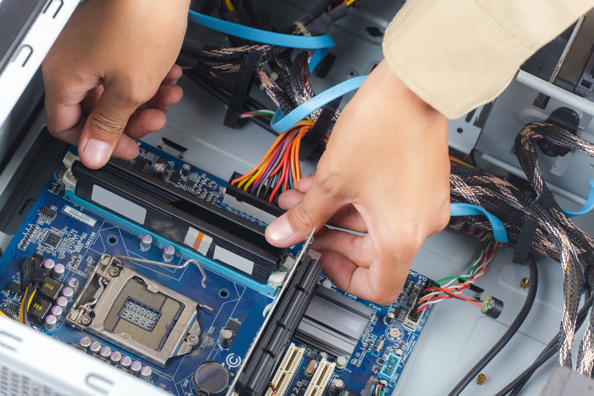 A technician's hands working on a motherboard inside a computer chassis